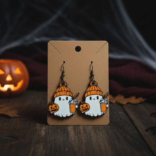 Halloween-themed ghost earrings on a cardboard backing with a dark background and pumpkin.